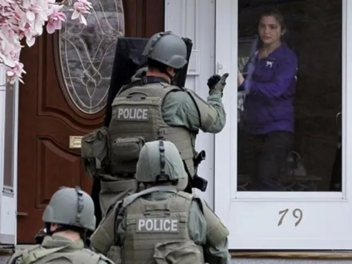 Woman opening door to an armed SWAT team