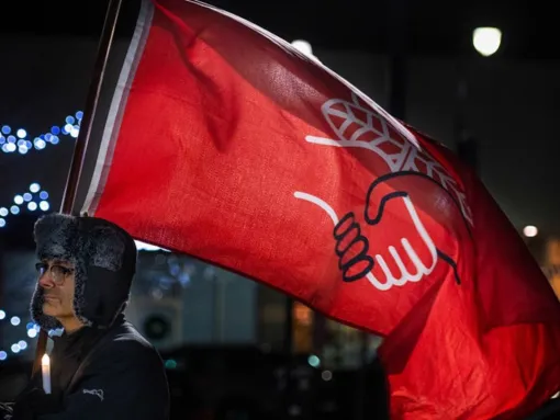 A man holds a Democratic Socialist of America flag at a vigil in Wilkes-Barre, Pennsylvania, November 20, 2022. (Aimee Dilger/SOPA Images/LightRocket via Getty Images)